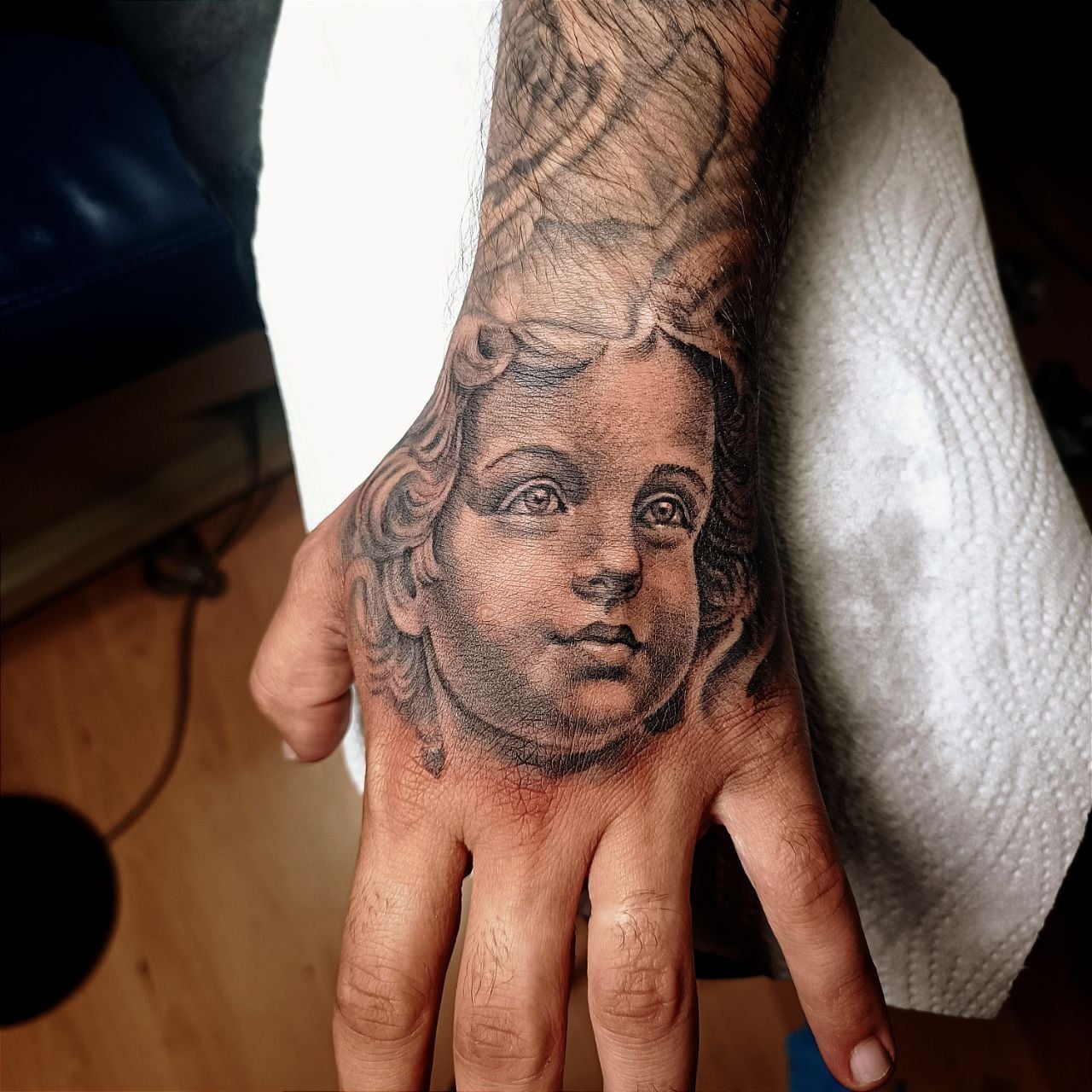 Black-and-grey tattoo – ancient Greek warrior in armor as sculpture on the upper arm